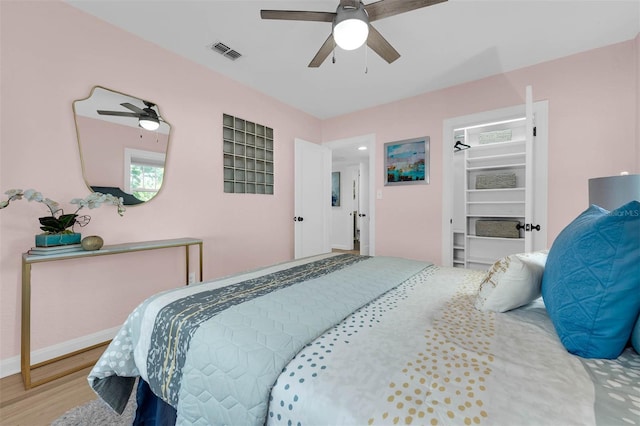 bedroom featuring baseboards, wood finished floors, visible vents, and ceiling fan