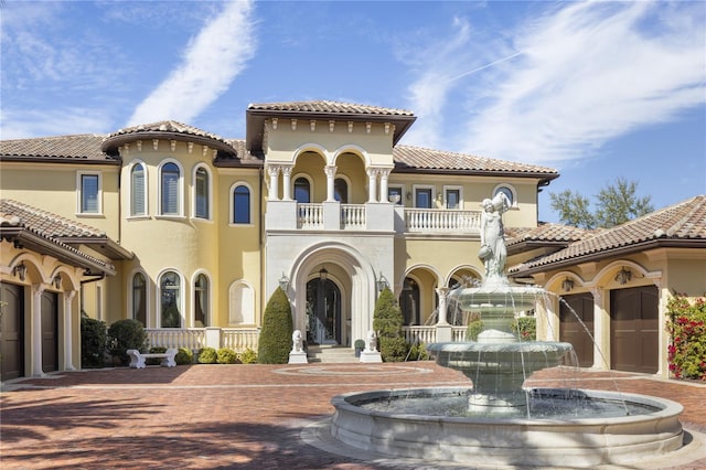 mediterranean / spanish-style house featuring stucco siding, decorative driveway, a garage, a balcony, and a tiled roof