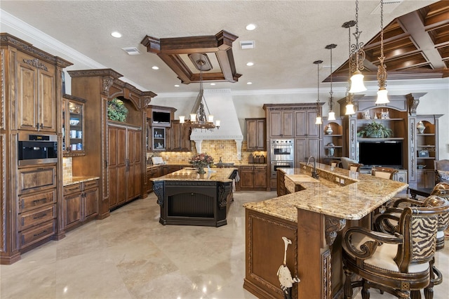 kitchen featuring custom exhaust hood, a large island with sink, a kitchen bar, double oven, and backsplash