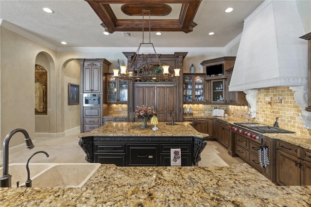 kitchen featuring custom exhaust hood, stainless steel gas stovetop, tasteful backsplash, and a sink