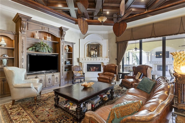 living area featuring beamed ceiling, ornamental molding, coffered ceiling, a lit fireplace, and a towering ceiling