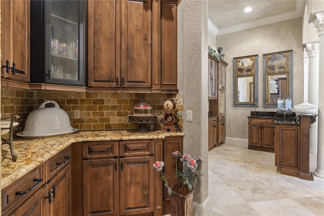 kitchen with light stone counters, decorative backsplash, glass insert cabinets, and ornamental molding