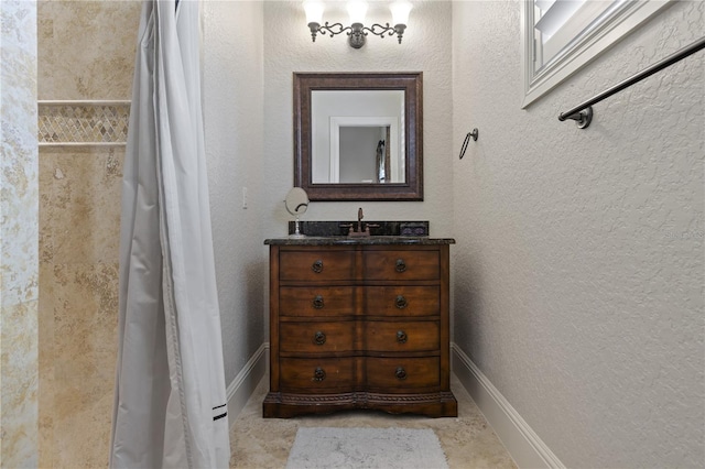 bathroom with baseboards, vanity, and a textured wall