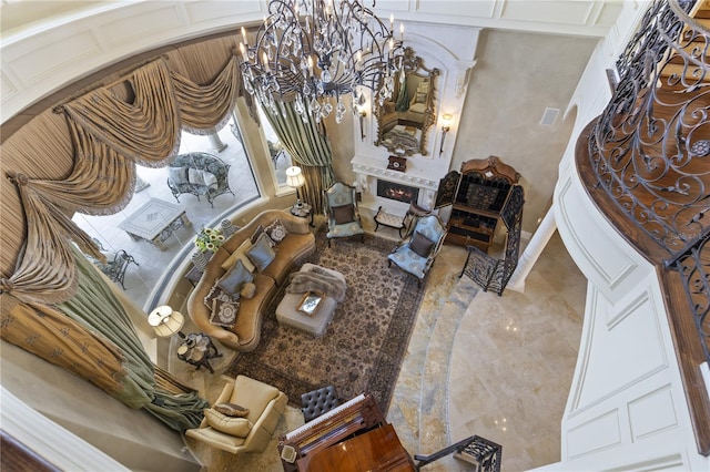 living area featuring an inviting chandelier and a lit fireplace