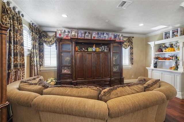 living area with visible vents, a healthy amount of sunlight, wood finished floors, and ornamental molding