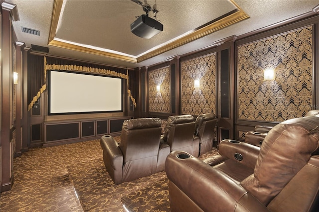 cinema room featuring carpet, visible vents, ornamental molding, a raised ceiling, and a decorative wall