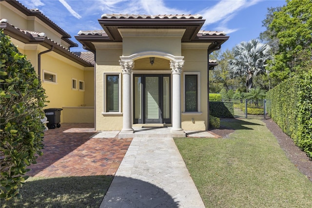 doorway to property featuring a tile roof, fence, and stucco siding