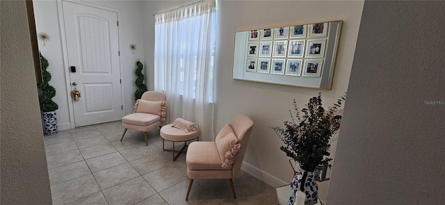 living area featuring tile patterned floors, a healthy amount of sunlight, and baseboards