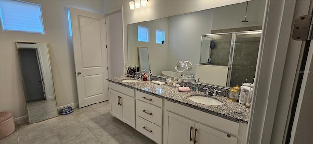 bathroom with a sink, baseboards, double vanity, and a shower stall