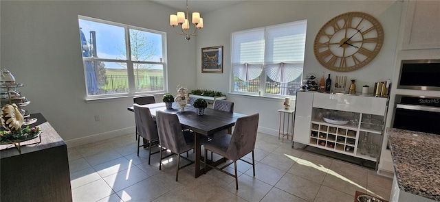 dining area with tile patterned flooring, an inviting chandelier, and baseboards