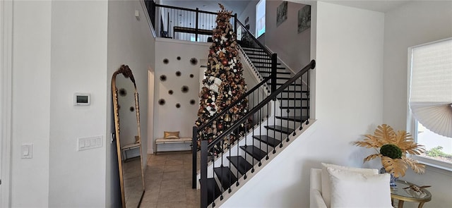 stairs featuring tile patterned flooring and a high ceiling