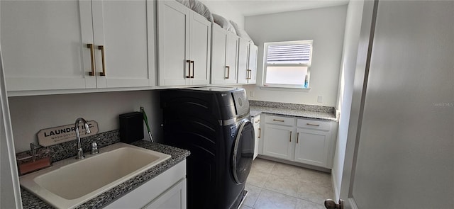 washroom featuring washing machine and dryer, light tile patterned floors, cabinet space, and a sink