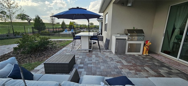 view of patio with grilling area, outdoor dining space, exterior kitchen, and a fenced backyard