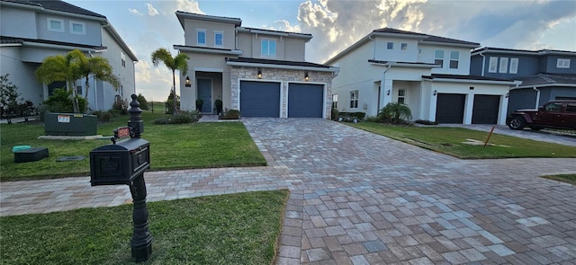 view of front facade featuring a front yard, decorative driveway, stone siding, and an attached garage