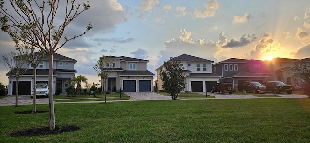 view of front of home with decorative driveway, a front yard, and an attached garage