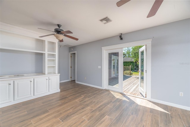 unfurnished living room featuring visible vents, ceiling fan, baseboards, and wood finished floors