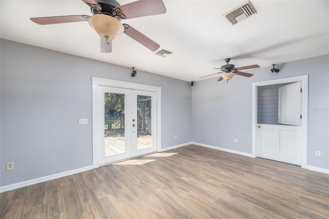 empty room with visible vents, baseboards, wood finished floors, and french doors