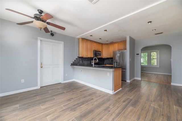 kitchen featuring visible vents, backsplash, appliances with stainless steel finishes, a peninsula, and arched walkways