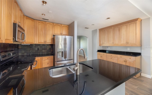 kitchen with a sink, stainless steel appliances, dark countertops, and visible vents