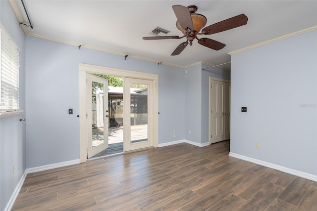 empty room featuring visible vents, wood finished floors, baseboards, and ornamental molding