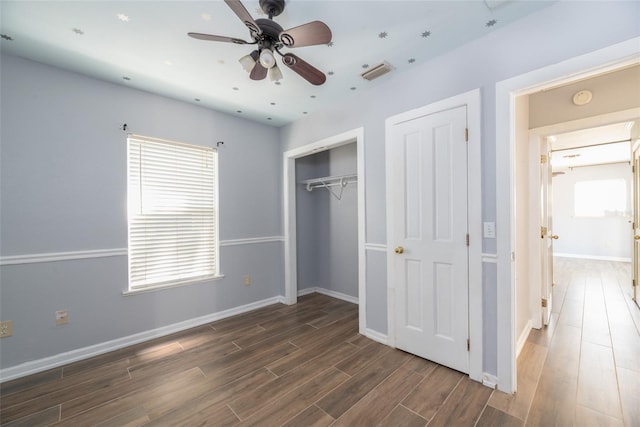 unfurnished bedroom with wood finished floors, visible vents, a closet, and baseboards