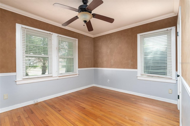 spare room with crown molding, wood finished floors, baseboards, and ceiling fan