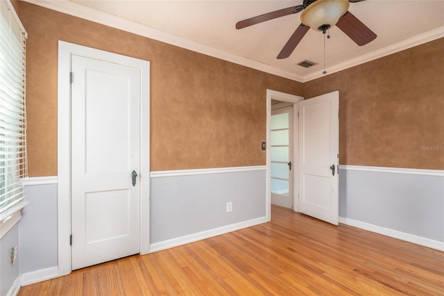 unfurnished room featuring visible vents, wood finished floors, baseboards, and ornamental molding