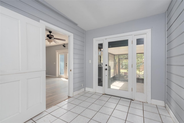 doorway to outside with light tile patterned flooring, ceiling fan, and baseboards