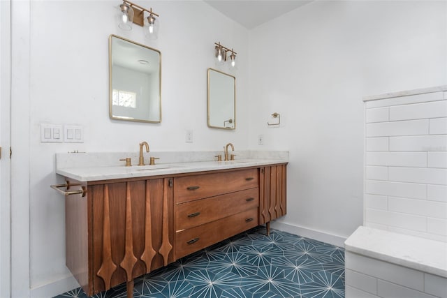 full bathroom featuring a sink, baseboards, and double vanity