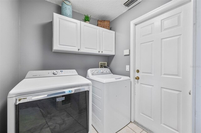 3580 Savannahs Trl, Merritt Island, FL 32953 - laundry room with a textured ceiling, visible vents, light tile patterned flooring, cabinet space, and washer and clothes dryer