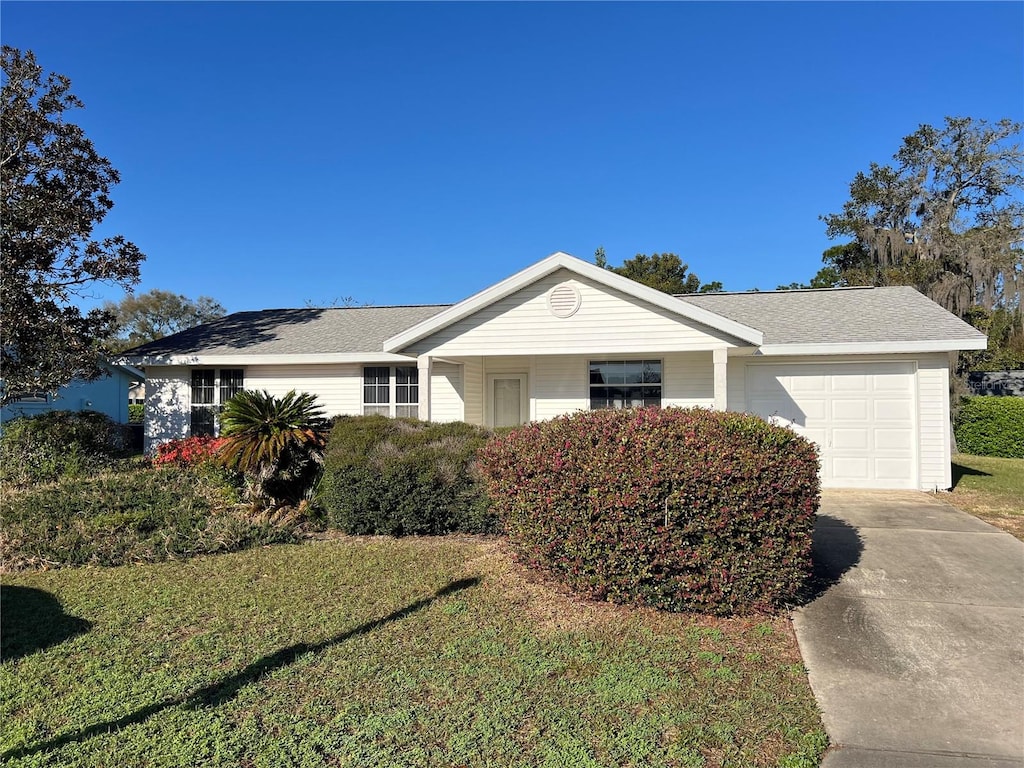 ranch-style house with concrete driveway, an attached garage, and a front lawn