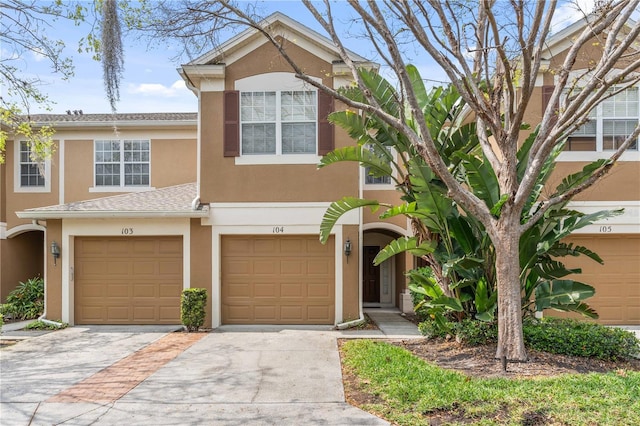 multi unit property featuring a shingled roof, a garage, driveway, and stucco siding