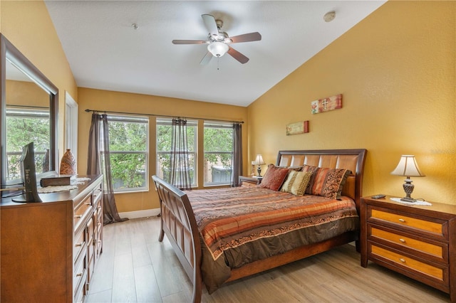 bedroom with vaulted ceiling, light wood-style flooring, and baseboards