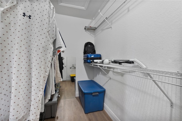 spacious closet with attic access and wood finished floors