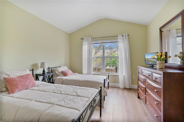 bedroom featuring light wood-type flooring, baseboards, and vaulted ceiling