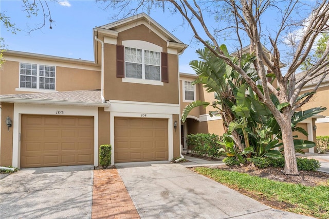 multi unit property with stucco siding, concrete driveway, and an attached garage