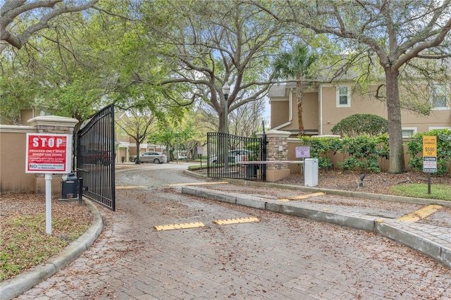 view of road featuring a gated entry, curbs, and a gate