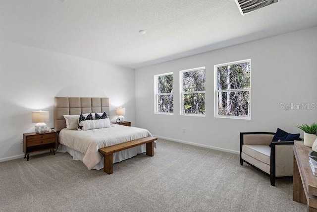 carpeted bedroom featuring visible vents, baseboards, and a textured ceiling