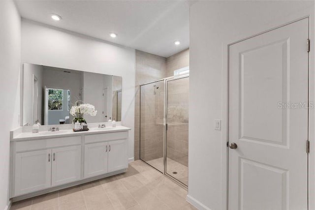 full bath with a sink, recessed lighting, a stall shower, and double vanity