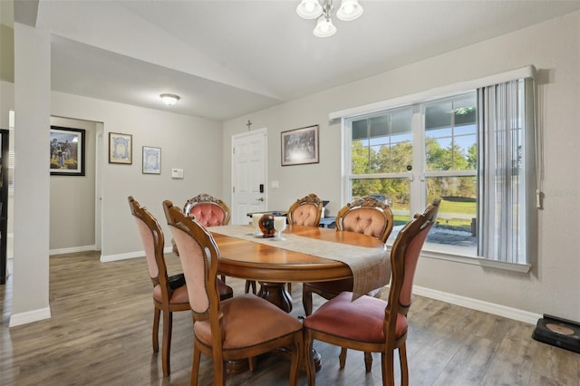 dining space featuring wood finished floors, baseboards, and vaulted ceiling