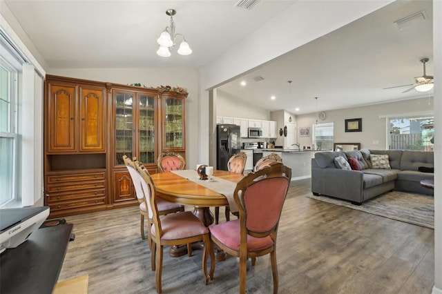 dining area with visible vents, lofted ceiling, recessed lighting, light wood-style floors, and ceiling fan with notable chandelier