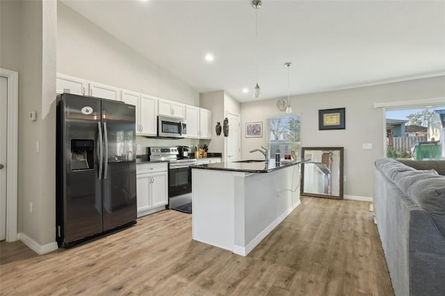 kitchen featuring dark countertops, light wood-style flooring, white cabinets, stainless steel appliances, and a sink