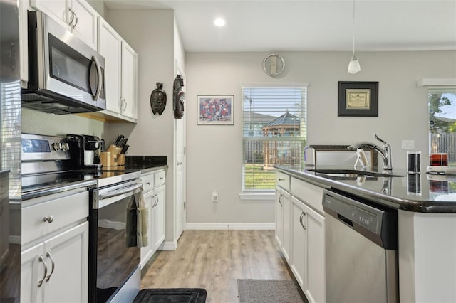 kitchen with dark countertops, white cabinetry, stainless steel appliances, and a sink