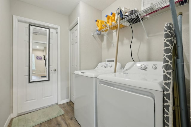 laundry area with baseboards, wood finished floors, laundry area, and washer and clothes dryer