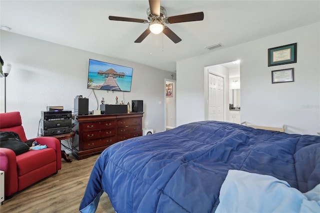 bedroom featuring wood finished floors, visible vents, ensuite bathroom, and ceiling fan