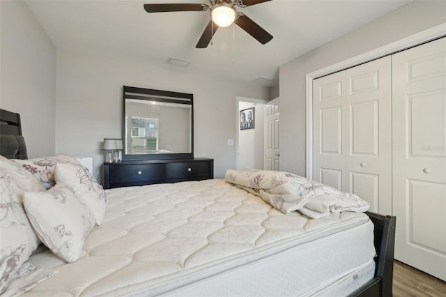 bedroom with a closet, wood finished floors, visible vents, and ceiling fan