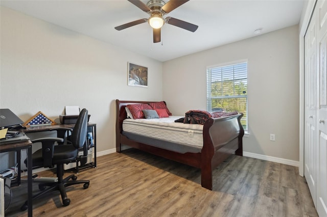 bedroom featuring a closet, baseboards, wood finished floors, and a ceiling fan