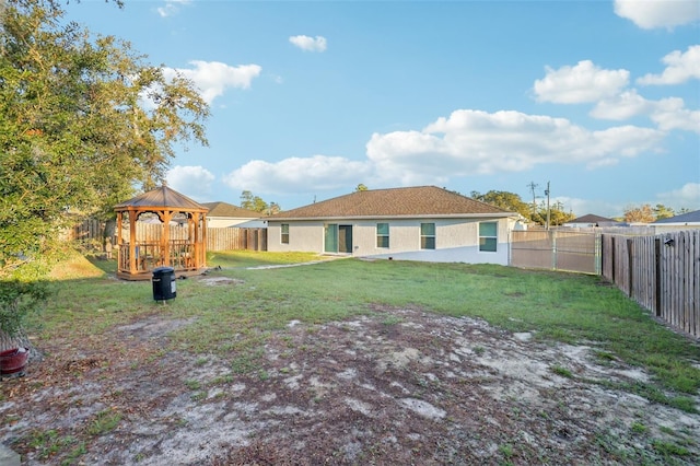 back of property featuring a gazebo, stucco siding, a lawn, and a fenced backyard