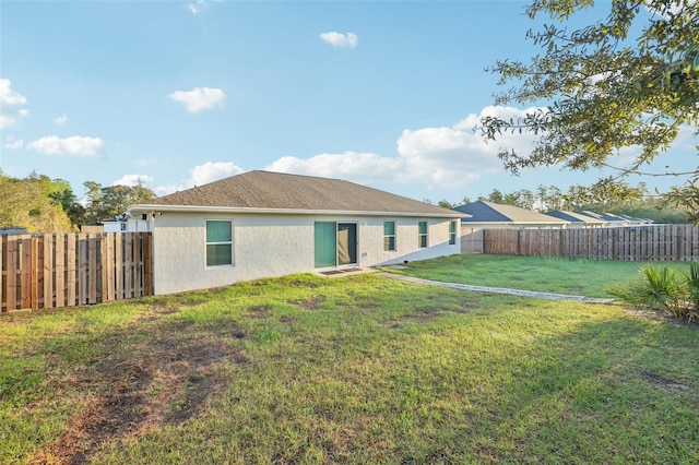 rear view of property featuring a fenced backyard, stucco siding, and a yard