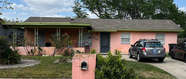 single story home with concrete block siding, a shingled roof, and covered porch